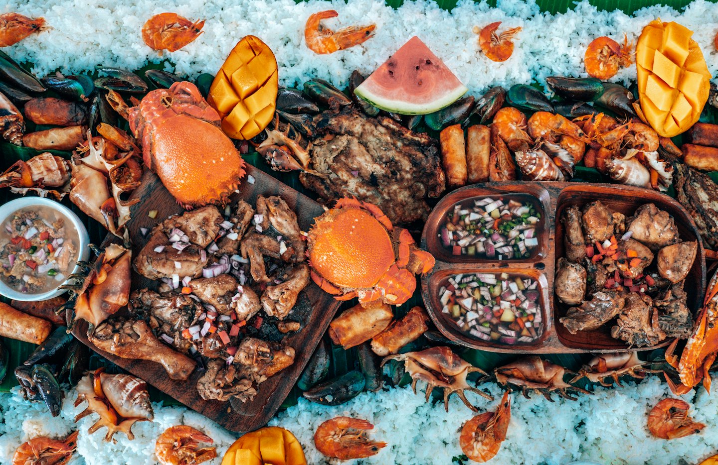 Boodle fight feast with seafood and rice on banana leaves.