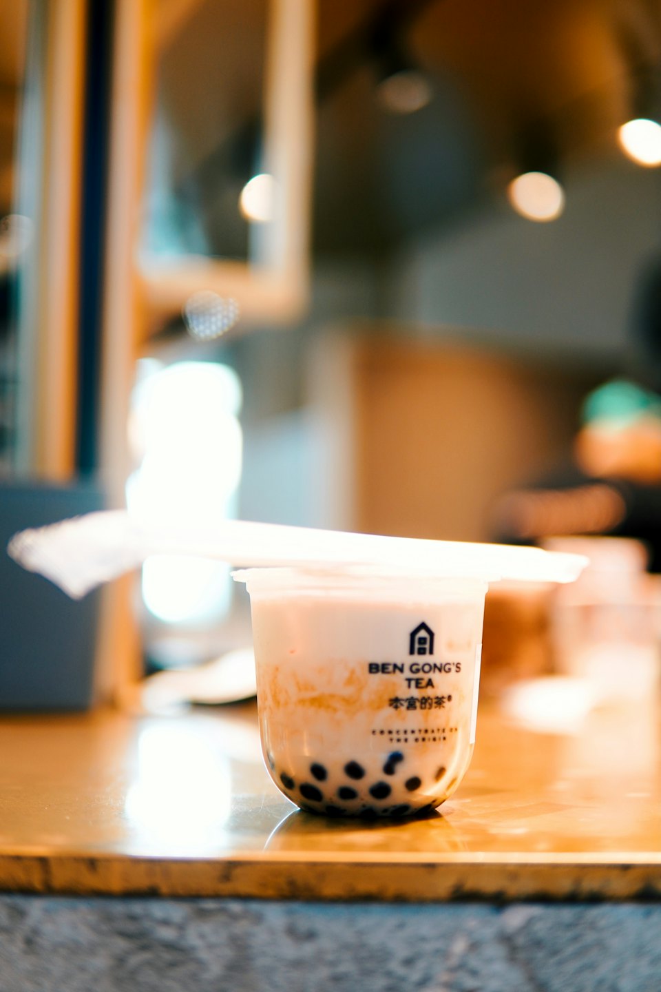 A cup of bubble tea rests on a wooden counter.