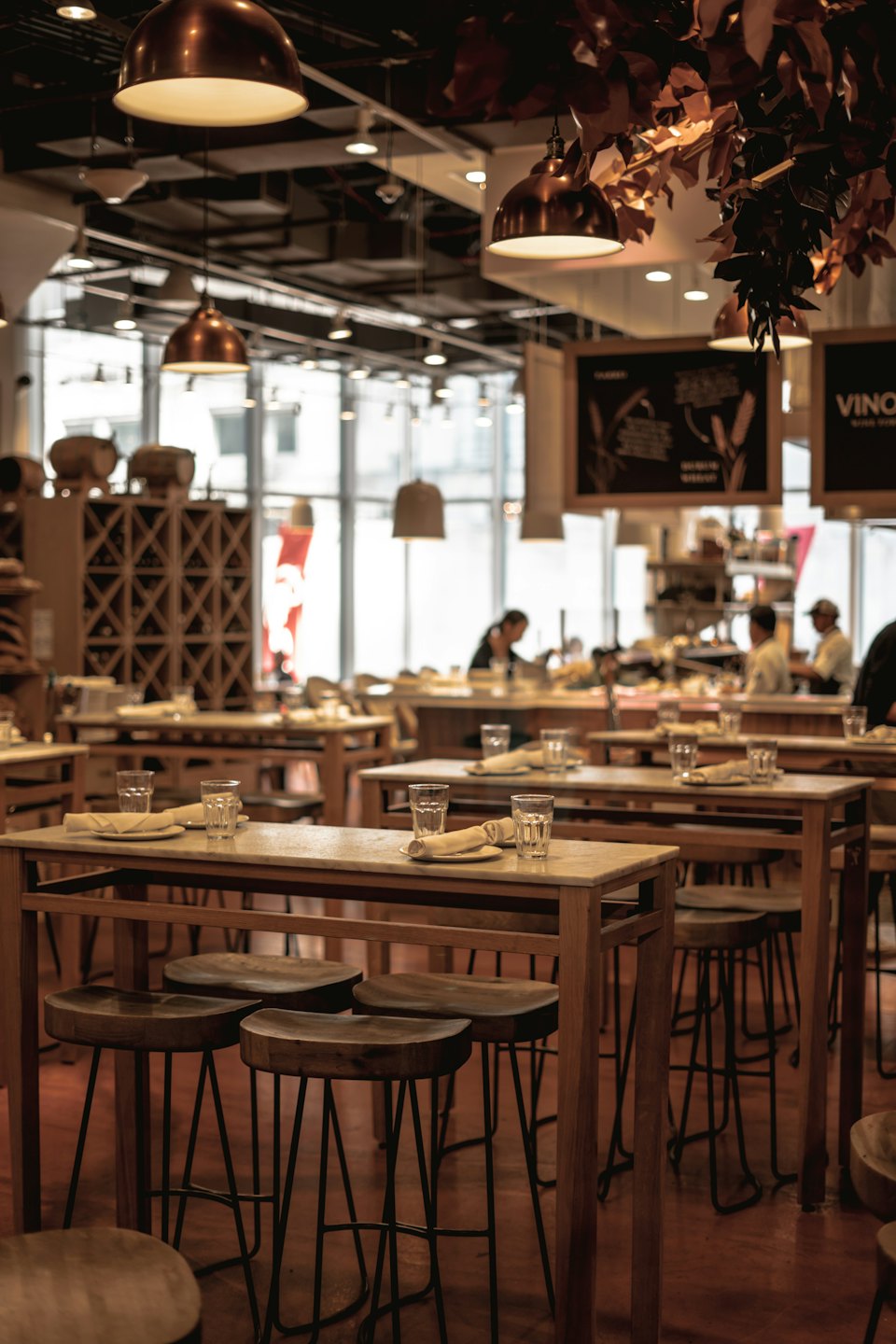 Restaurant dining area with wooden tables, marble tops, and bar stools.