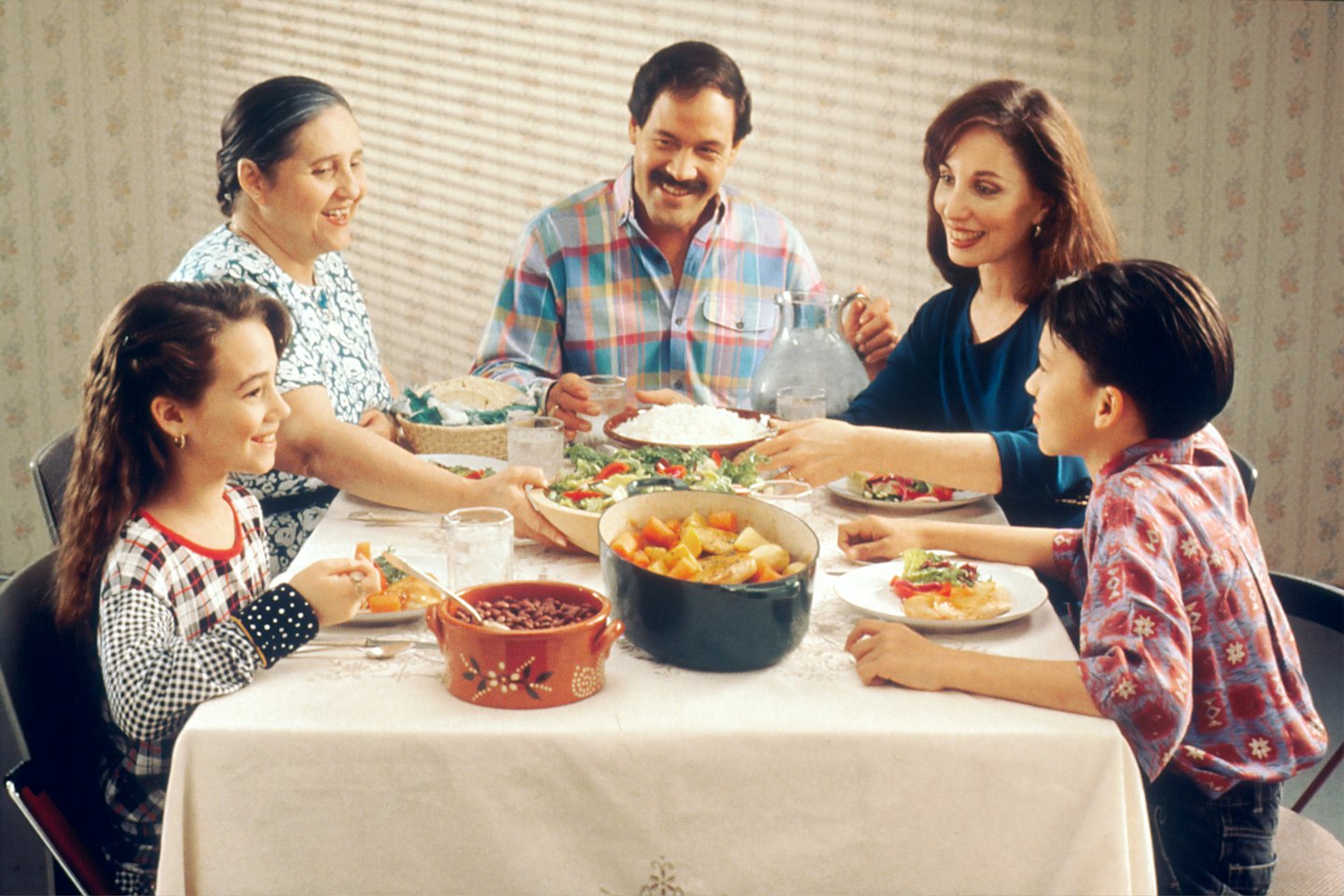 Family of five enjoys a meal together at a dining table.